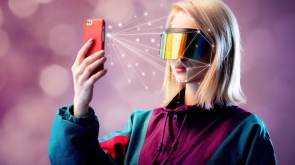 Blonde in VR glasses hold mobile phone with face scanning algorithm