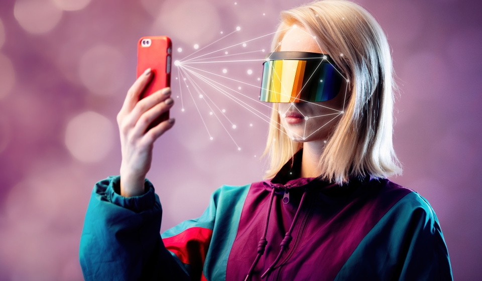 Blonde in VR glasses hold mobile phone with face scanning algorithm